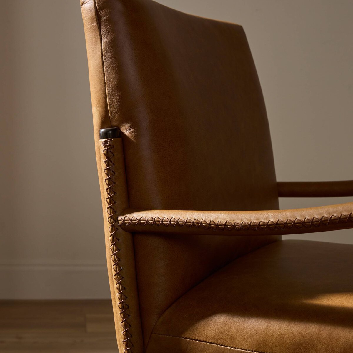 Four Hands Quill Dining Armchair in Chaps Saddle leather with leather-wrapped iron legs, close-up detail of leather, view 1