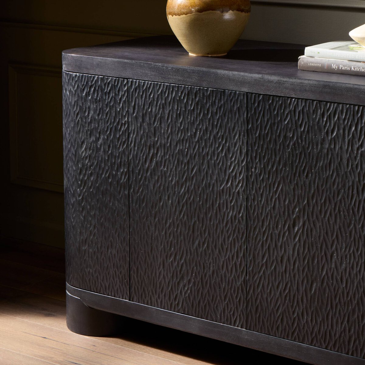 Four Hands Shevall Sideboard in carved black mango with cylinder legs, close-up detail of carved door front, view 1