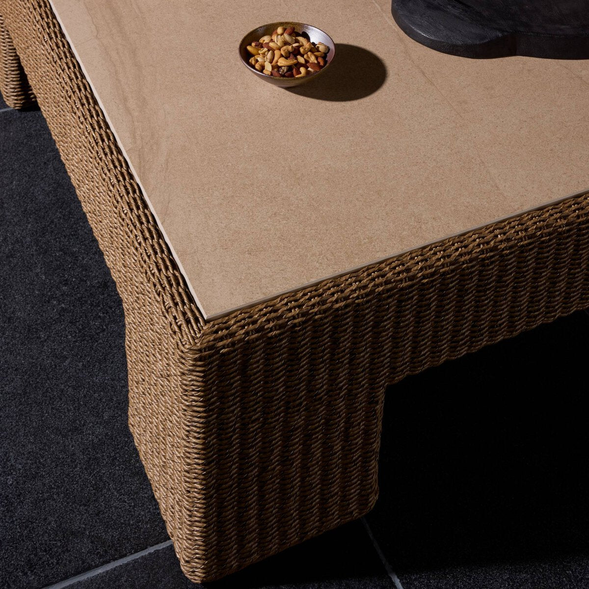 Four Hands Maris Outdoor Coffee Table in faux dark hyacinth with sintered stone top, close-up detail of hyacinth weave, view 1
