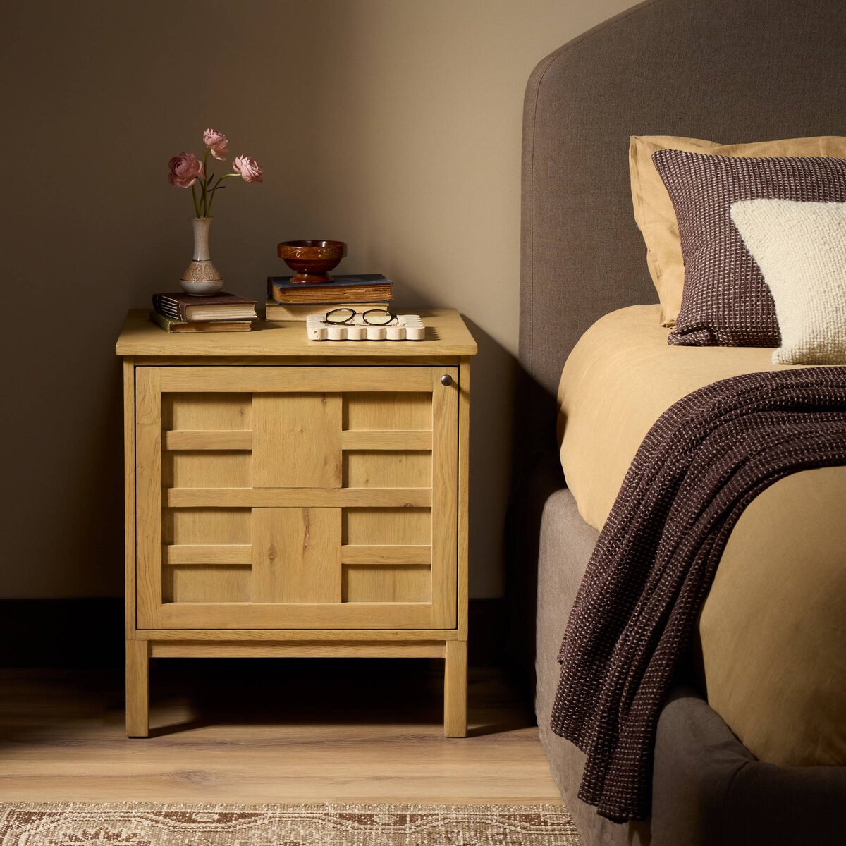 Four Hands Alessio Nightstand left orientation in aged natural oak, styled view