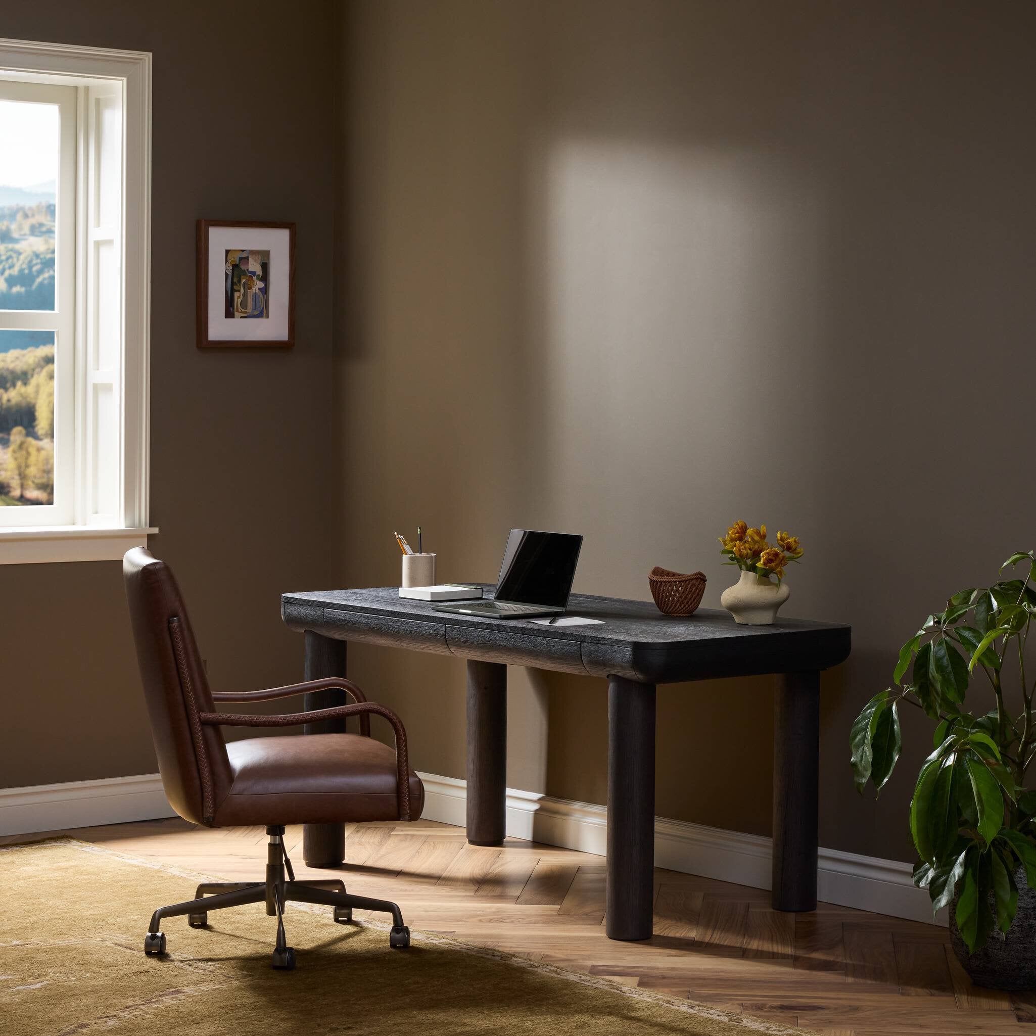 Four Hands Taylor Worn Black Oak Standing Desk styled in a room setting