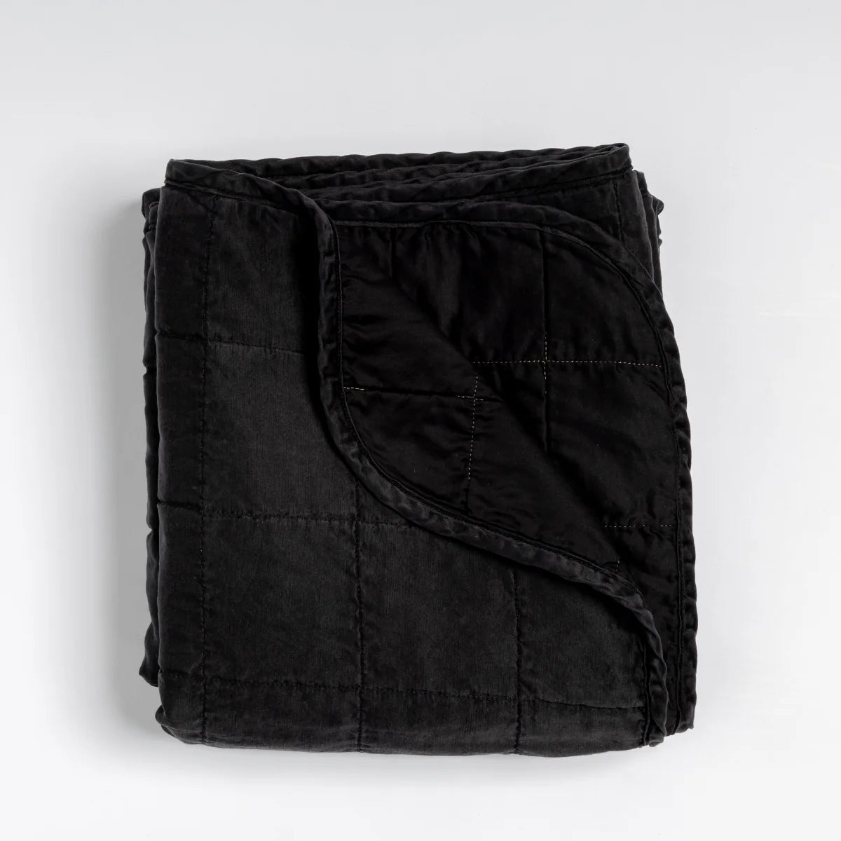 Bella Notte Sel Throw Blanket in quilted charmeuse, draped over a bench for texture
