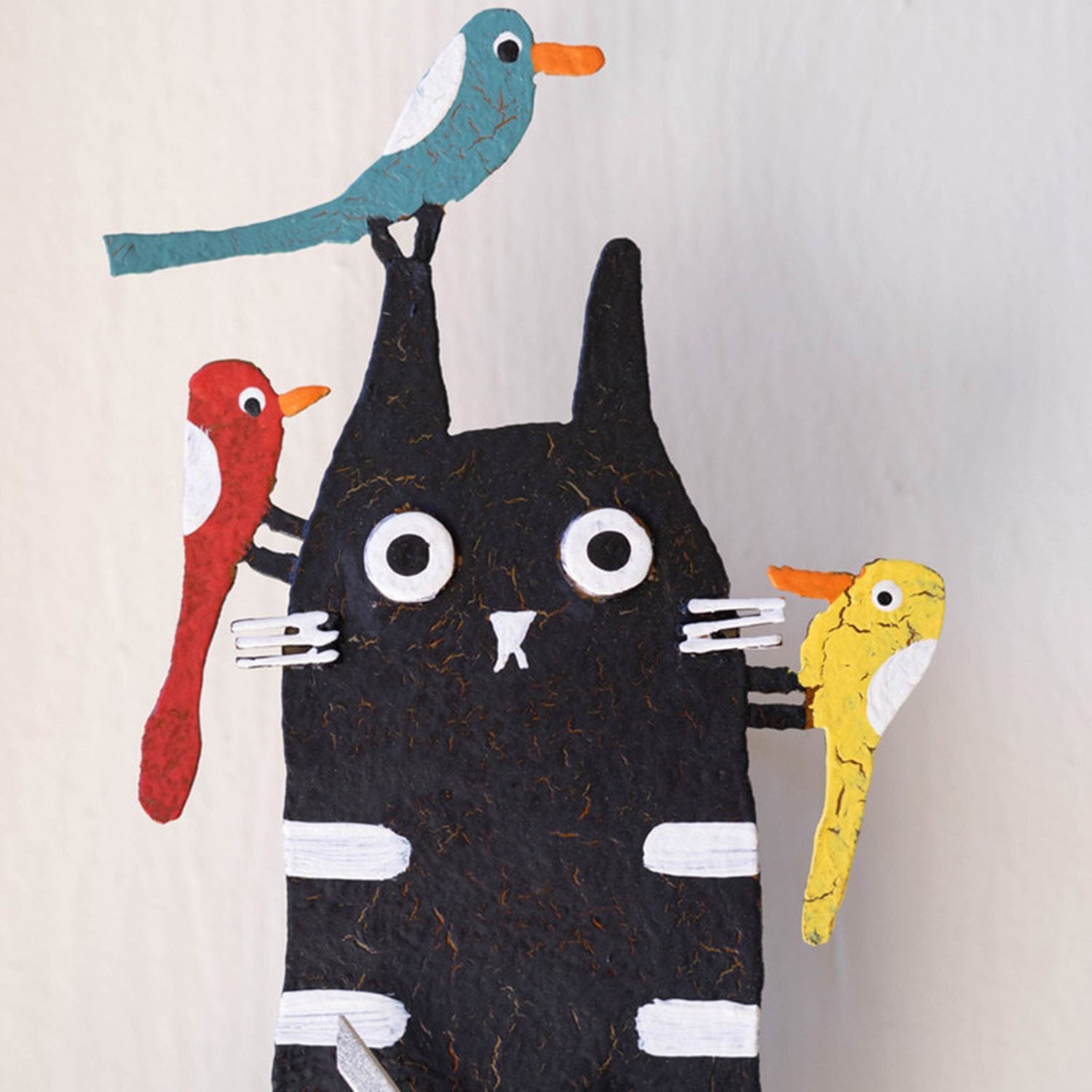 Close-up of the wide-eyed cat and colorful perched birds