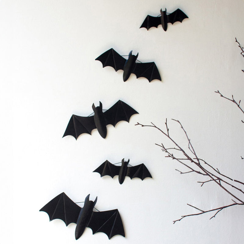 Black paper bats arranged in a swarm on a living room wall
